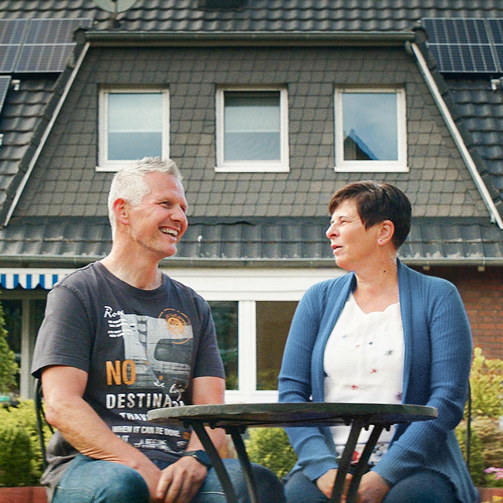 Infravoltaic Kunden sitzen im Garten am Tisch und reden über ihre Infravoltaic Solaranlage