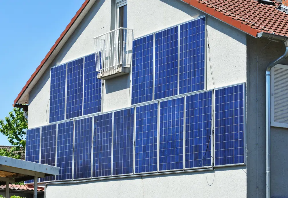 Bild von Fassaden-PV. Es hängen mehrere Module untereinander und nebeneinander an der Hausfassade.