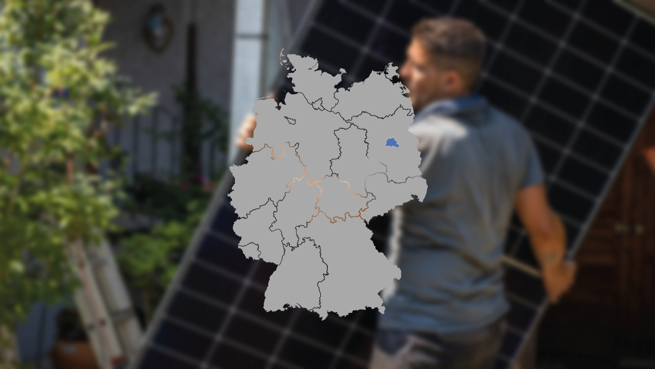 Solarmonteur mit Solarmodul verschwommen im Hintergrund und Deutschlandkarte im Vordergrund, wo Berlin blau markiert ist, um die Photovoltaik-Förderung dort zu zeigen