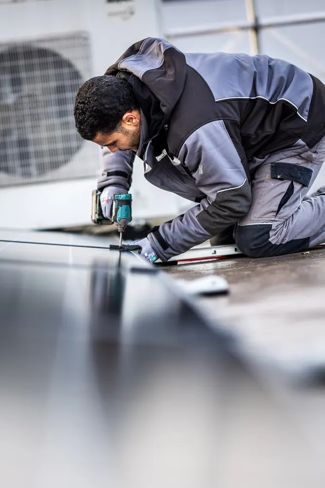 Infravoltaic Handwerker montiert Solarmodule auf einem Dach eines Gewerbekunden