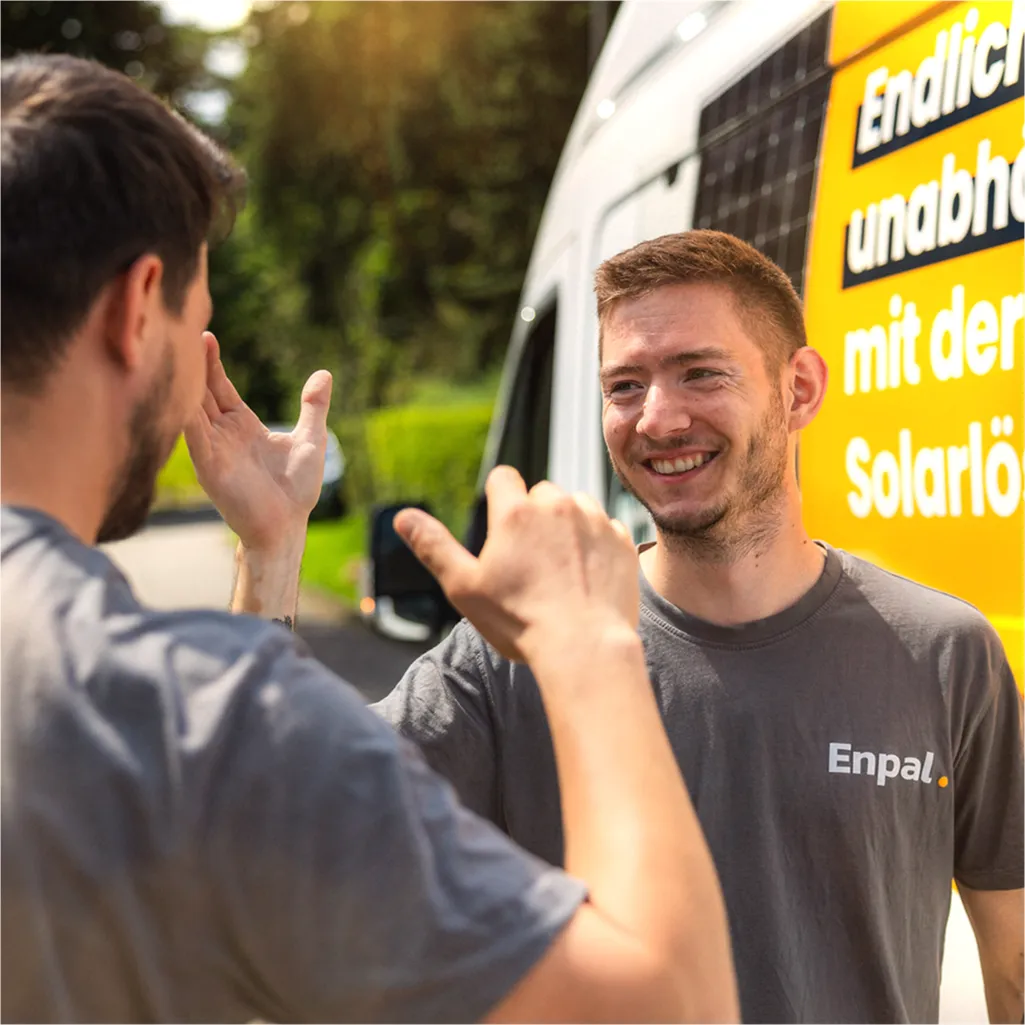 Zwei Infravoltaic Handwerker geben sich die Hand und ein Infravoltaic Transporter steht im Hintergrund