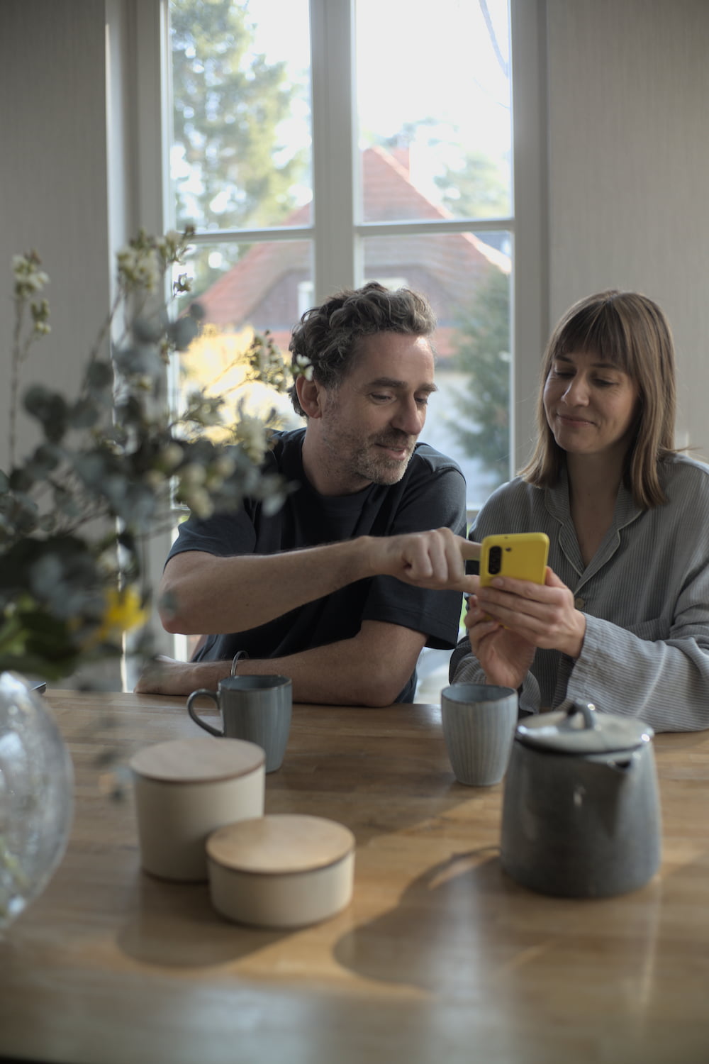 Infravoltaic Kunden sitzen am Esstisch und schauen auf die Infravoltaic App am Smartphone