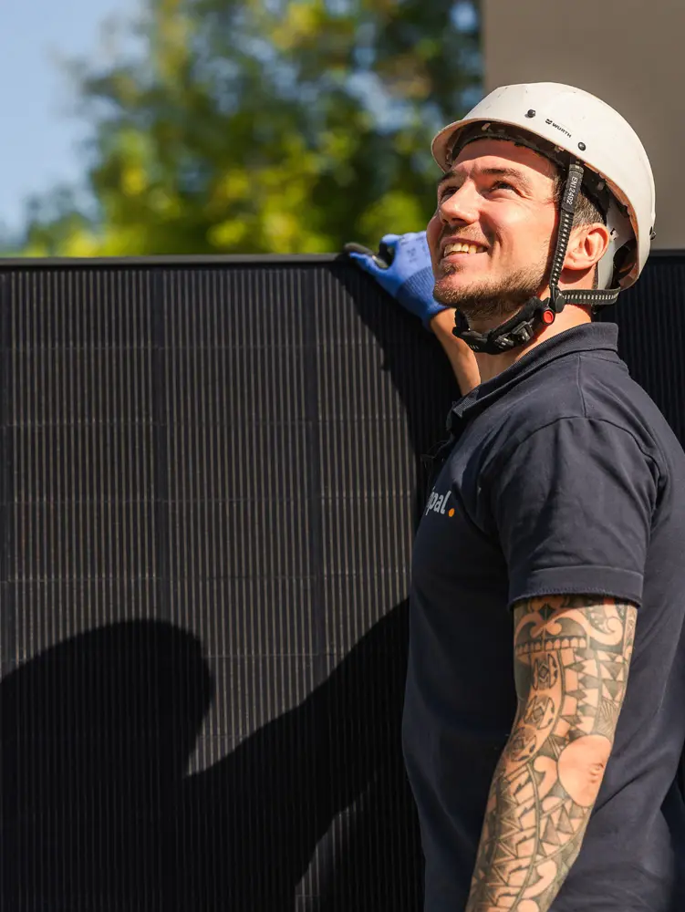 Enpal-Monteur mit Solarmodul blickt hoch aufs Dach
