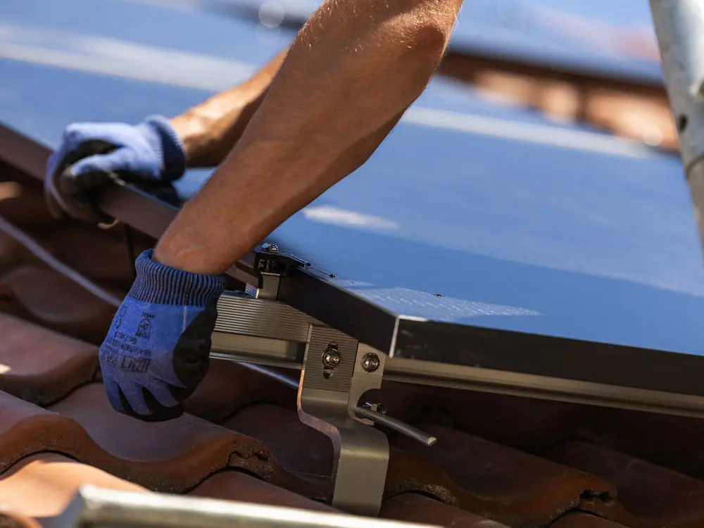 Die Hände eines Infravoltaic Handwerkers bei der Anbringung von den Kabeln der Solarmodule.